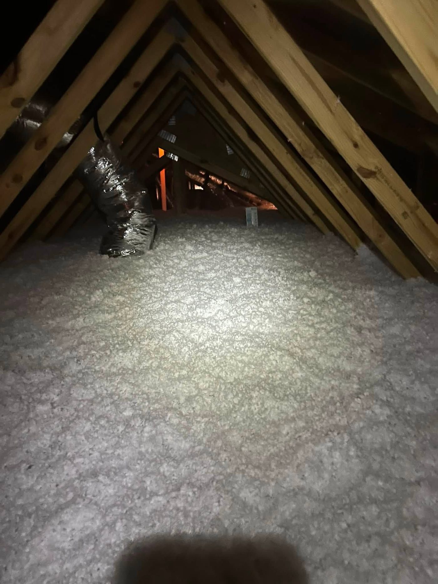 Blown-in attic insulation at full depth with a depth marker card visible