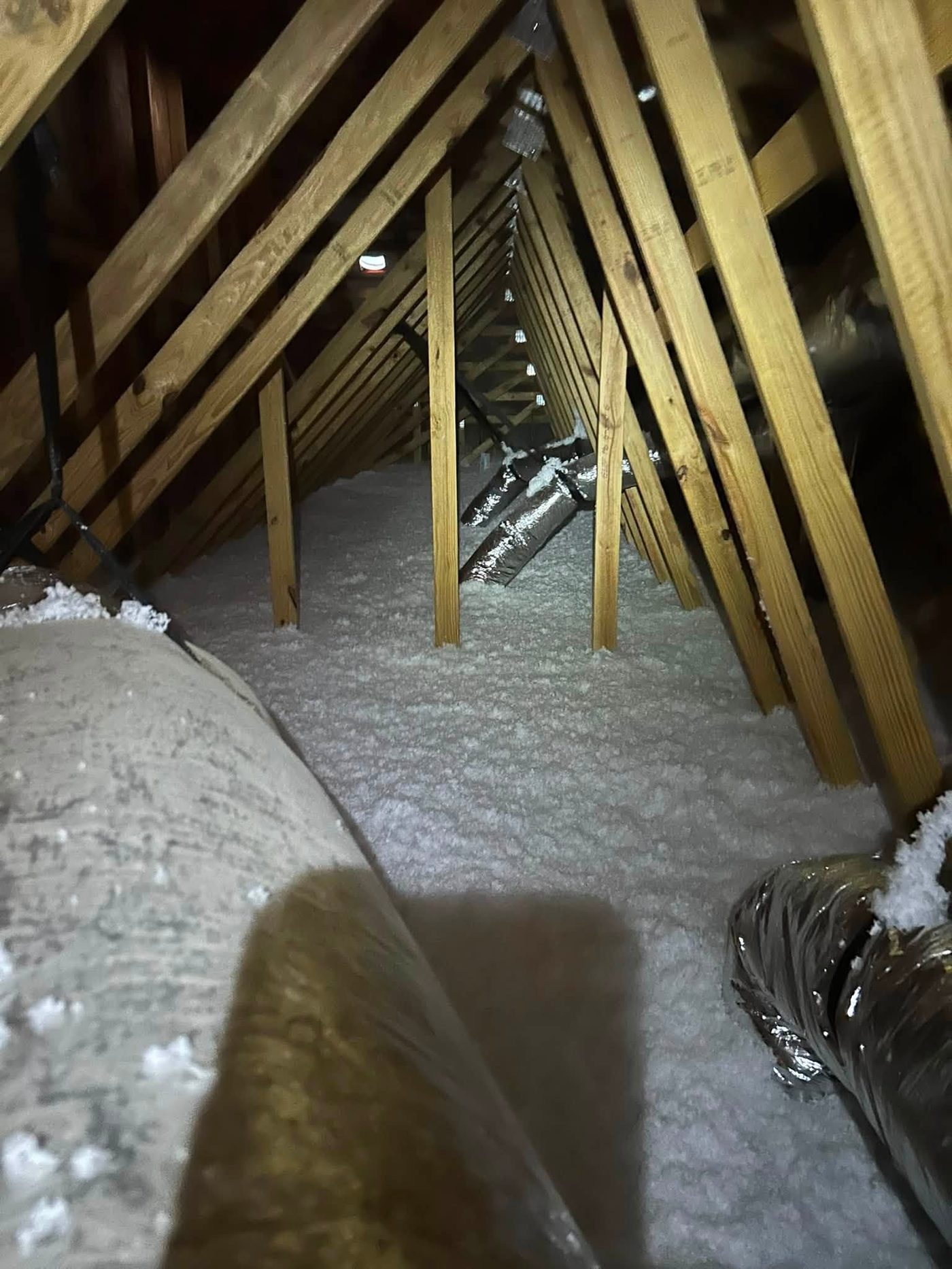 Attic after insulation replacement - fresh blown-in insulation covering the floor around ductwork